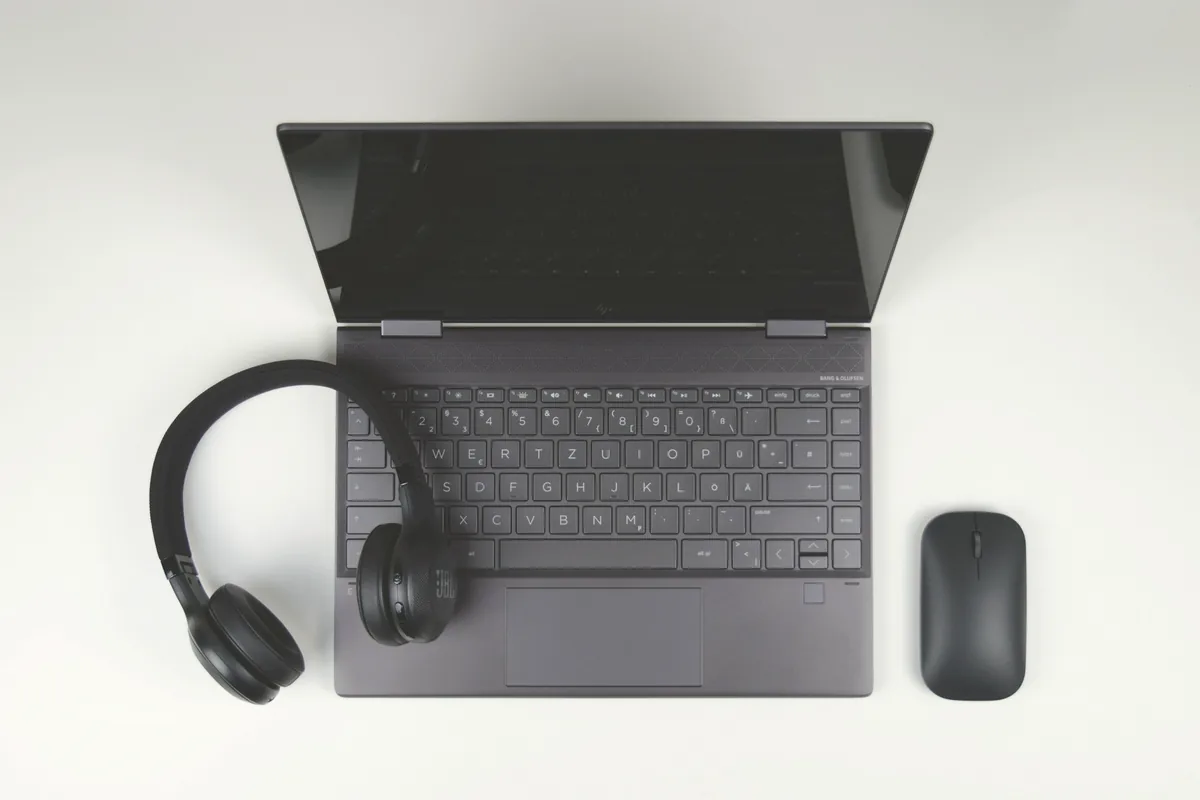Ordinateur portable et casque audio posés sur une table blanche, vus de dessus