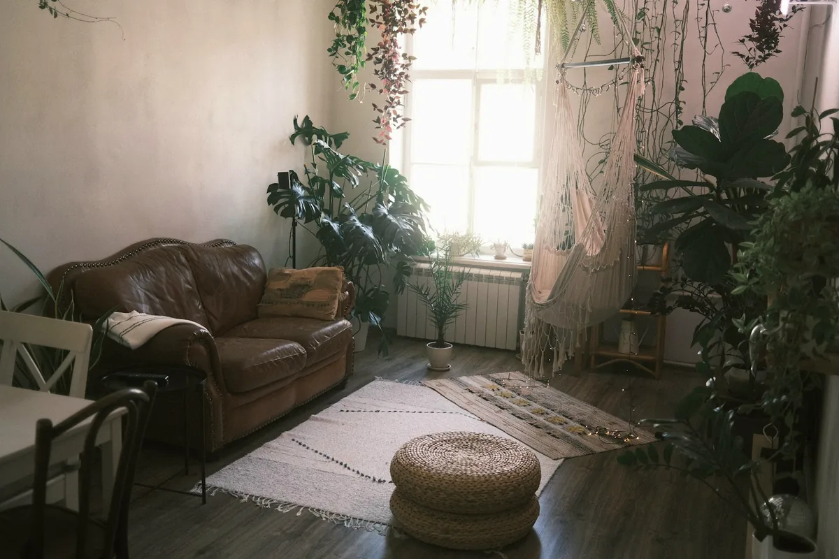 Pièce calme avec un canapé en cuir, des plantes et un pouf tressé